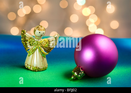 Weihnachten Dekoration Engelsstatue und Christbaumkugel mit Lichtern im Hintergrund auf bunten Stoff angeordnet Stockfoto