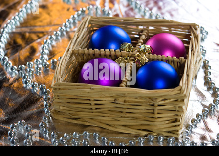 Weihnachtskugeln, angeordnet in einem Korb mit Silberperlen Stockfoto