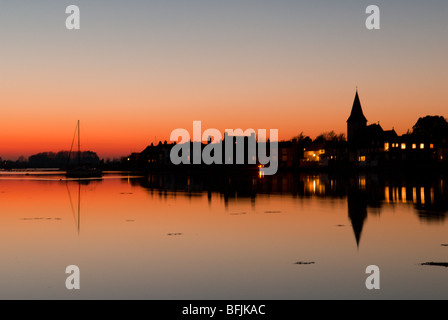 Farbenfroher Sonnenuntergang über dem Wasser zum Dorf Bosham und zur Kirche mit der Flut, wunderschönes stilles Wasser, Sussex, Großbritannien Stockfoto