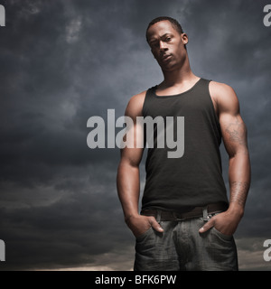 Afrikanischer Mann mit Händen in den Taschen, Gewitterwolken in Ferne Stockfoto