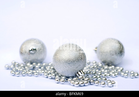 Drei silberne Weihnachtsbaumkugeln an einer Schnur aus silbernen Perlen auf weißem Hintergrund Stockfoto
