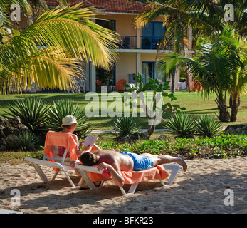 Ein paar entspannte in einem Resort. Frau ist ein Buch lesen, Mann, die Festlegung von Gerben, Karibik Resort Stockfoto