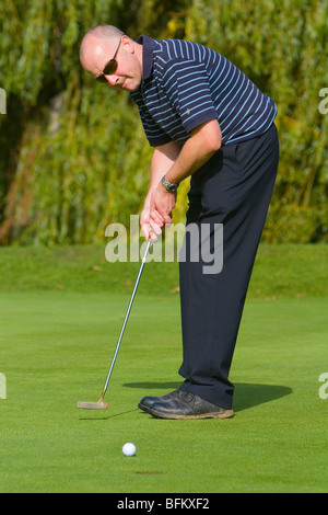 Mittleren Alters weiße männliche Golfer gerade seinen Ball auf dem Weg zum Loch beim Anziehen des Grüns Stockfoto