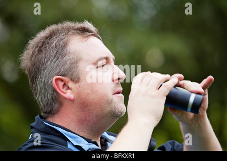 Ein weißer Mann mittleren Alters Golf zu spielen und mit Fernglas auf dem Golfplatz Stockfoto