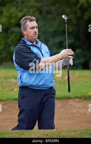 Ein weißer Mann, Golf spielen und ein Schuss aus einem Sandbunker Stockfoto