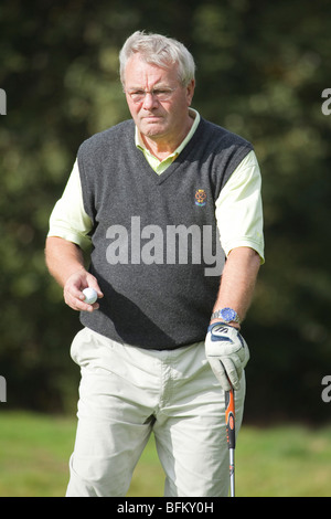 Ein senior weißer Mann mit Brille hält einen Club und einen weißen Golfball Golf spielen Stockfoto