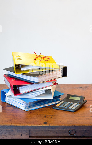 Haufen von farbigen Ringbücher, Gläser und Rechner auf Schreibtisch aus Holz Stockfoto