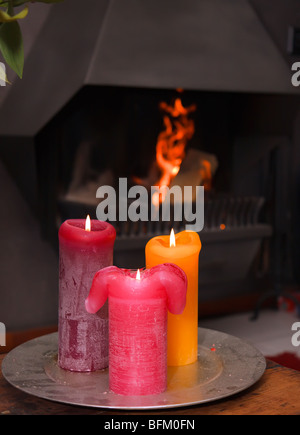 Satz von drei brennende Kerzen vor einem brennenden Kamin Stockfoto