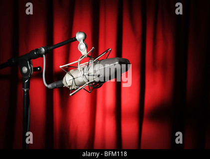 Vintage Mikrofon mit Spotlight über einem roten Vorhang Stockfoto