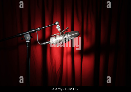 Vintage Mikrofon mit Spotlight über einem roten Vorhang Stockfoto