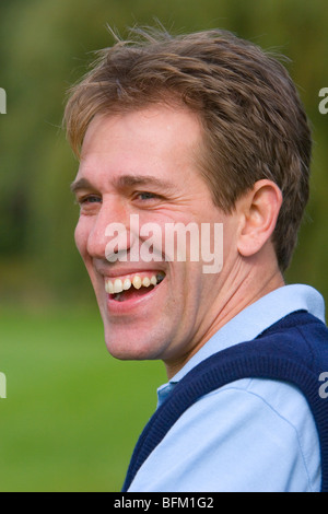 Weißer Mann mittleren Alters stehen außen betrachtet von der Kamera entfernt und lächelnd Stockfoto