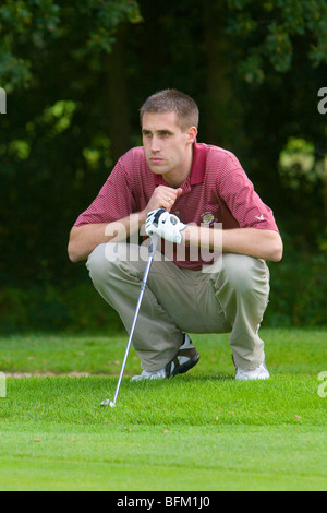 Ein junger weißen männlichen Golfer Futter sein nächstes schossen während der Umsetzung von der Kante des Grüns Stockfoto
