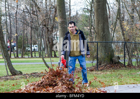 Ein Hausbesitzer Mann bläst verlässt. Eine typische Herbst Szene in urbanen Amerika. Die Blätter sind in die Luft bläst. Stockfoto