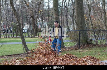 Ein Hausbesitzer Mann bläst verlässt. Eine typische Herbst Szene in urbanen Amerika. Die Blätter sind in die Luft bläst. Stockfoto