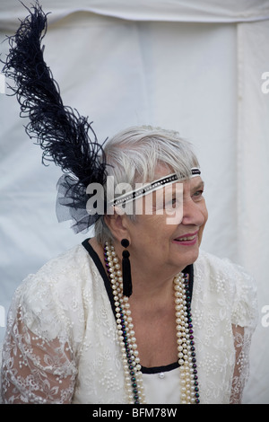 Dame in schöner weißer 20er-Flapper-Tracht mit großer schwarzer Feder im Kopfband. GROSSBRITANNIEN Stockfoto