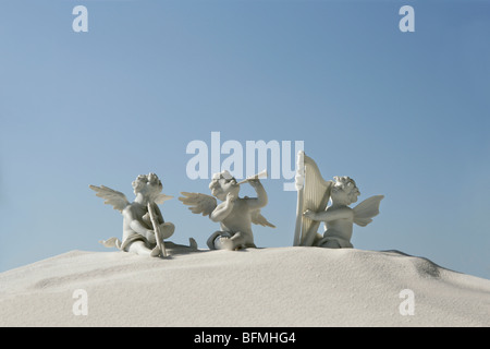 Engel Figuren mit Musikinstrumenten auf weißem Sand Stockfoto