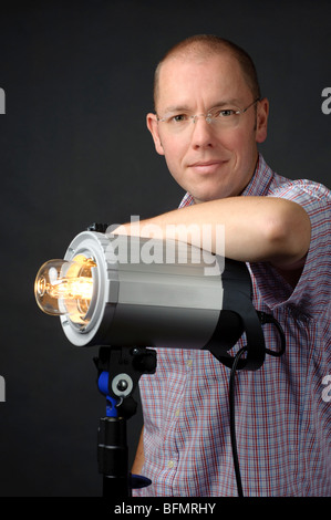 Voll isolierte Studio Bild von einem jungen Fotografen mit einem Studioblitz Stockfoto
