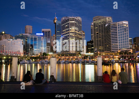 Australien, New South Wales, Sydney.  Besucher auf der Uferpromenade am Darling Harbour, Blick auf die Skyline der Stadt. Stockfoto