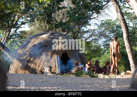 Namibia, Buschmannland. Eine Gruppe von Bushman (oder San) Dorfbewohner außerhalb ihren Rasen strohgedeckten Unterschlupf in dem Dorf Nhoqma Stockfoto