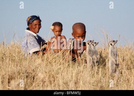 Botswana, Makgadikgadi. Buschmänner Kinder spielen in die trockene Gräser der Kalahari, beobachtet von ihrer Mutter. Stockfoto