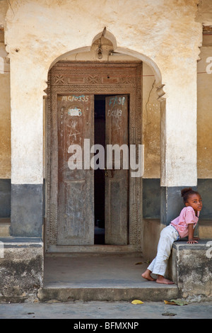 Tansania, Sansibar, Stonetown. Ein junges Mädchen vor ihrem Haus in einem der Stone Town s Labyrinth von engen Gassen. Stockfoto