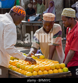 Tansania, Sansibar. Kunden wählen Sie lokal angebauten Orangen an einem Stand am Mkokotoni Markt im Nordwesten der Insel Sansibar. Stockfoto