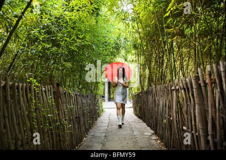 China, Beijing, ethnische Minderheiten Park, ein Mädchen mit Sonnenschirm zu Fuß durch einen Bambushain (MR) Stockfoto