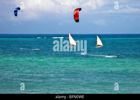 Kenia, Mombasa. Zwei kite-Surfer Geschwindigkeit vom Ausleger-Kanus Segeln in den klaren Gewässern des Diani Beach. Stockfoto