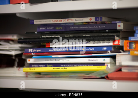 Haufen von Sport und Bewegung Lehrbücher auf einem Regal in einer Schule-PE-Abteilung in der uk selektiven Fokus Stockfoto