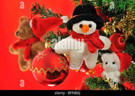 Schneemann, Teddybär und Glocken hängen im Weihnachtsbaum Stockfoto