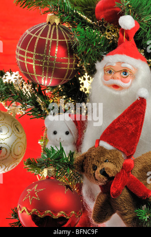 Santa Claus / Weihnachtsmann, Teddybär und Glocken hängen im Baum Stockfoto