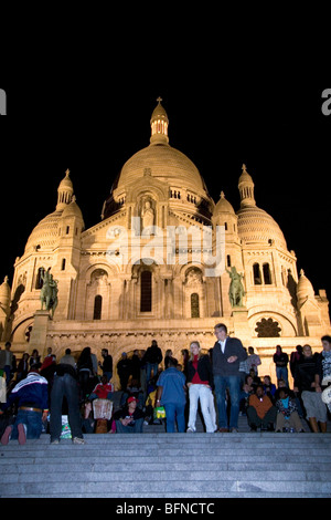 Menschen versammeln sich auf den Stufen der Basilika Sacre-Coeur in der Nacht in Paris, Frankreich. Stockfoto