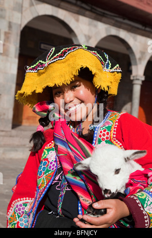 Hübsches peruanische Mädchen in traditioneller Tracht mit Lamm in Plaza de Armas, Cuzco, Peru Stockfoto