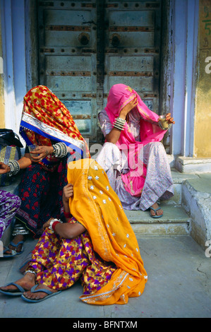 Frauen sitzen mit Ghoghat auf Türstufen; Pushkar Messe; Rajasthan; Indien; asien Stockfoto