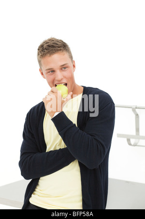 hübscher blonder Mann Essen Apfel; isoliert auf weiss Stockfoto