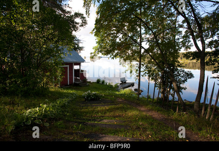 Fußweg zu einem kleinen roten Holz- Sauna am See, Finnland Stockfoto