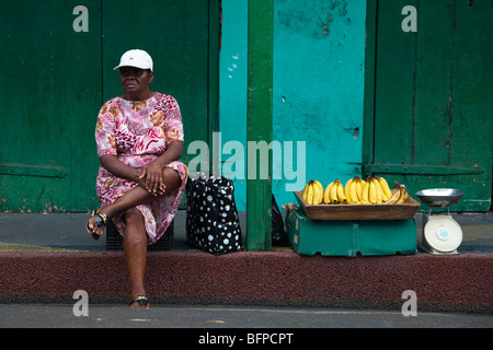 Schwarze Frau verkaufen Bananen aus einem Pflaster straßenkante in St. Johns, Antigua und Barbuda, West Indies Stockfoto