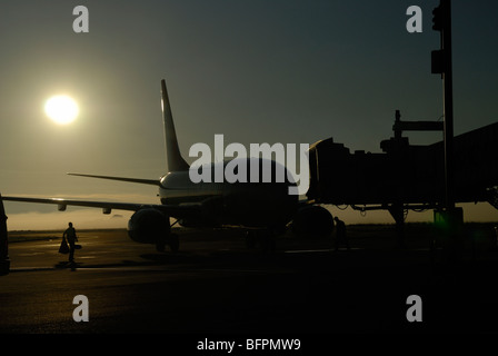 Flugzeuge stationiert an Transfer-Brücke, Silhouette gegen die Morgensonne, Flughafen Curitiba, Brasilien Stockfoto