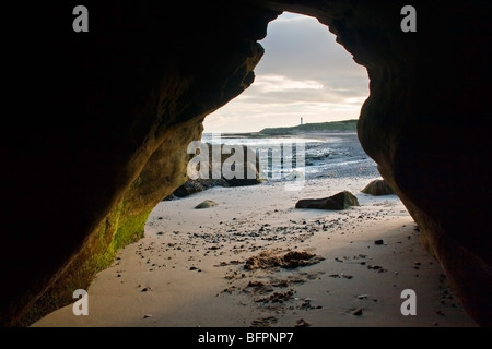 Blick in Richtung Weststrand Lossiemouth und Covesea Skerrie Leuchtturm aus einer Höhle in der Nähe von Hopeman, Moray, Schottland, Vereinigtes Königreich Stockfoto