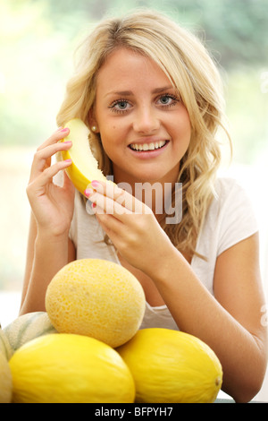 Glücklich ziemlich junges Mädchen eine frische gesunde Melone auf der Suche nach ihrem Wohlbefinden mit gesunder Ernährung und einer Ernährung mit Obst essen Stockfoto