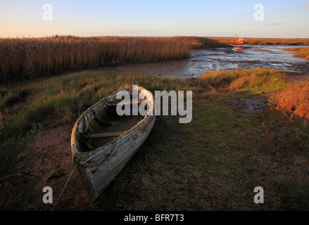 Ein Holzboot in Brancaster Staithe an der North Norfolk Küste, mit sonnigen Schilf im Hintergrund. Stockfoto