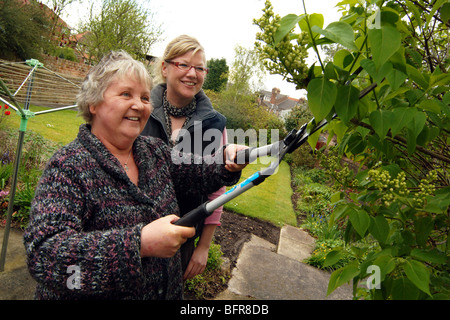 Wohnhaft und Unterstützung Arbeiter schneiden die Hecke von der Wohnungsbaugesellschaft Garten für Menschen mit psychischen Gesundheitsproblemen, York. Stockfoto