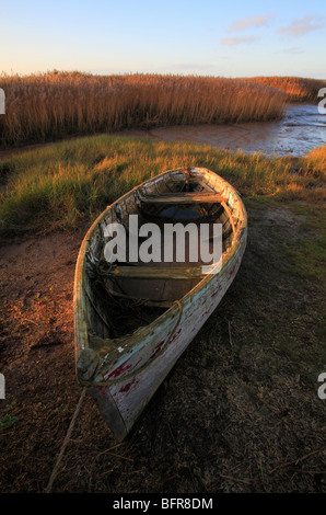 Ein Holzboot in Brancaster Staithe an der North Norfolk Küste, mit sonnigen Schilf im Hintergrund. Stockfoto