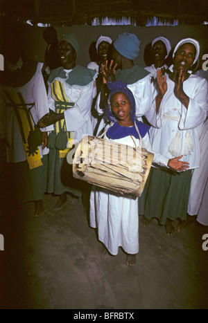 Junges Mädchen spielen eine Trommel mit dem Chor der Kirche von Botswana Heilung Händeklatschen und singen Stockfoto