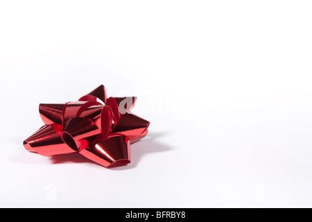 Rot glänzende Geschenk Bogen vor weißem Hintergrund aus niedrigen Sicht isoliert. Stockfoto