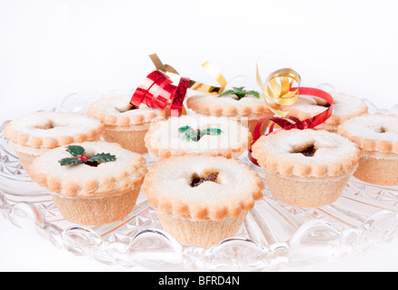 Glasplatte von Sweet Mince Pies verziert mit Bändern und gefälschte Holly. Stockfoto