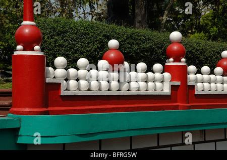 Ungewöhnliche oder dekorative rote und türkisfarbene Wand mit weißen Kugeln im Tiger Balm Gardens Chinese Theme Park, Singapur Stockfoto