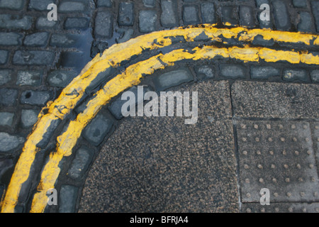 Kopfsteinpflaster Straßenpflaster und doppelte gelbe Linien um die Ecke gehen Stockfoto