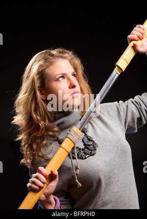 Junge Frau mit Samurai-Schwert. Auf dunklem Hintergrund. Stockfoto