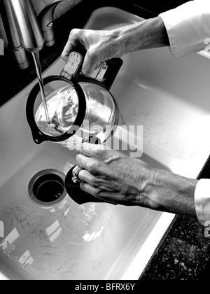 Frau, Wasser in die Kaffee Kanne Krug vom Wasserhahn im Waschbecken in der Küche Nahaufnahme Stockfoto